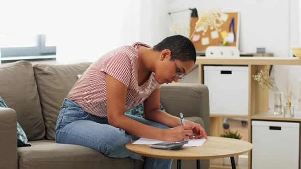 African Woman with Papers and Calculator at Home