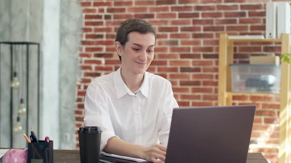 Businesswoman Works at a Laptop Sitting at Desk and Rejoices Gesticulating Hands Under Falling