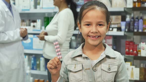 Little Girl Holding Medicine and Showing Thumbs Up