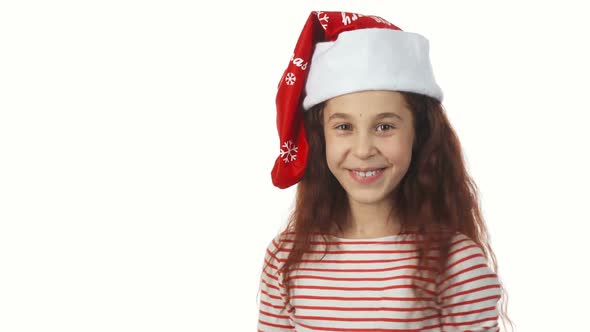 A Girl in a Santa Claus Cap Smiles at the Camera
