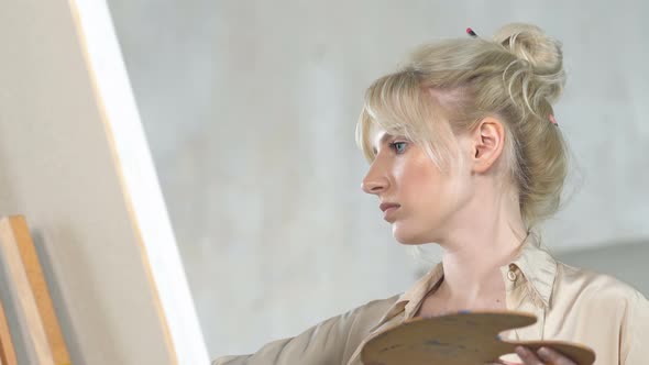 Portrait of Artist Woman Holding Paint Palette and Drawing at The Easel