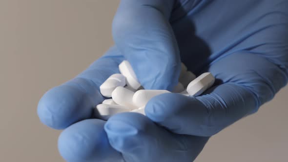 Closeup Shot of a Hand in Rubber Gloves Holding White Pills