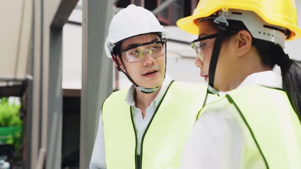 Asian colleague workers people wearing protective safety helmet and work at construction site.