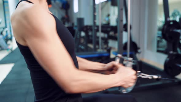 Woman in a Black Top Performs an Exercise for Pumping the Press and Biceps 