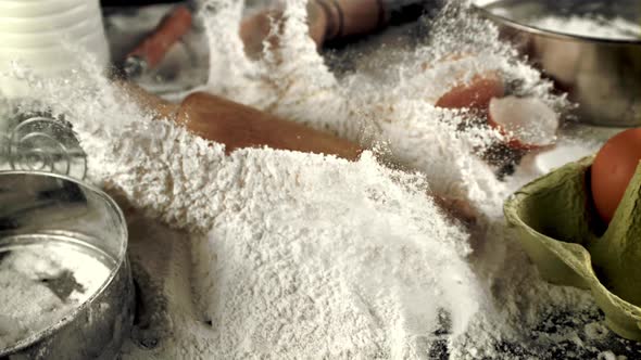 Super Slow Motion Wooden Rolling Pin Falls in a Pile of Flour on the Table