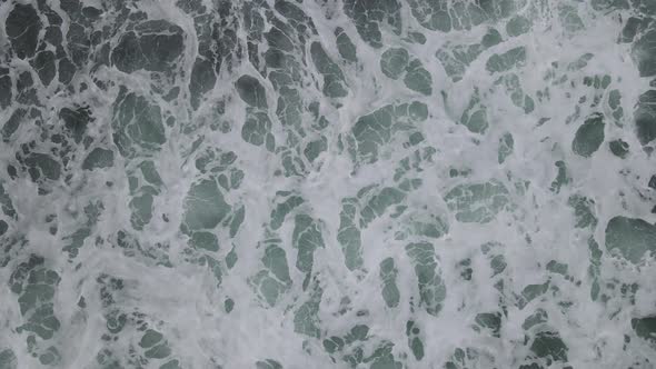 Top down aerial view of giant ocean waves crashing and foaming