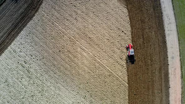 Red tractor plowing a spring field, Poland, aerial view