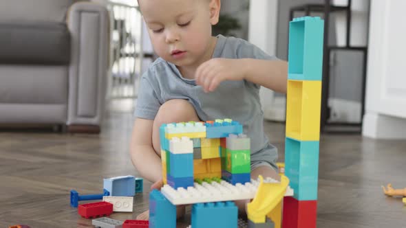 Little Child Boy Playing Building Bricks Blocks Sitting on Floor in Living Room alt