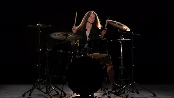 Drummer Girl Starts Playing Energetic Music, She Smiles. Black Background