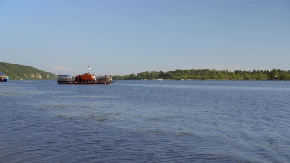 A Ship Transports a Truck To the Other Side of the River. River View.