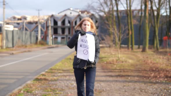 Slim Caucasian Woman with No Housing Needed Placard Walking to Camera Showing Message