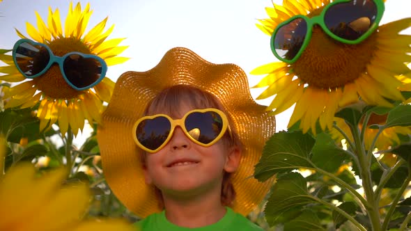 Happy child having fun in spring field of sunflowers, Slow motion alt