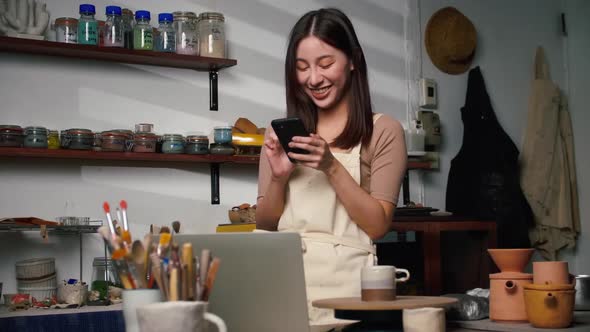 A female ceramist taking a photo of the new collection of ceramic mugs in the workshop.