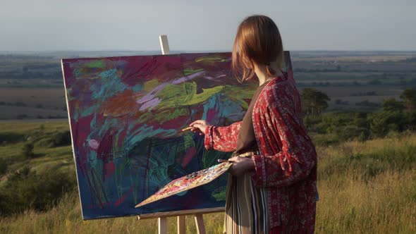 Young Girl Artist Paints Picture In Nature. Outrageous Girl Makes Brush Strokes On The Easel