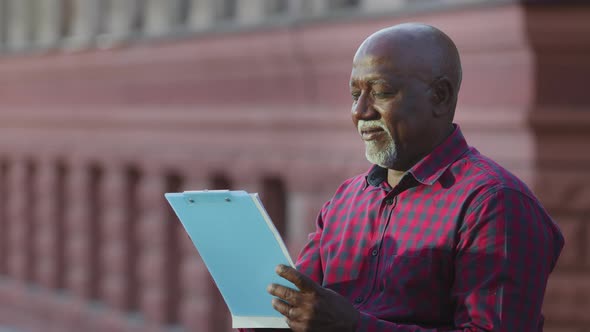 Mature Adult African American Male Specialist Standing Outdoors with Paper Clipboard