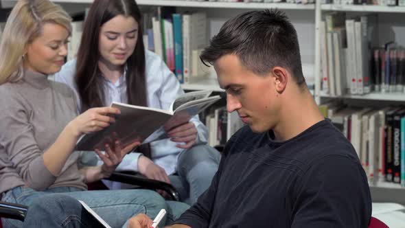 Handsome Male Student Smiling To the Camera, While Doing Homework at Library