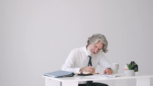 Old Man in Smart Look Working at the Table