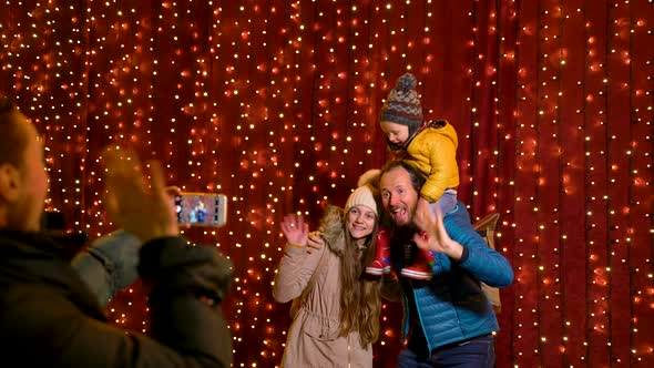 Mother taking photo of family at Christmas market on the night.