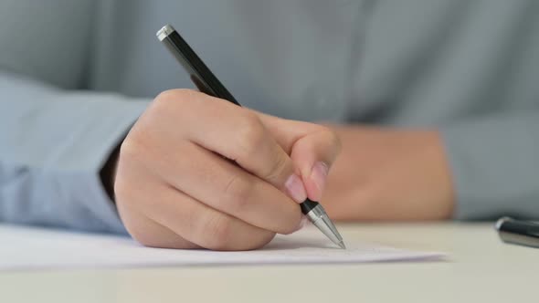 Close Up of African Woman Writing on Paper with Pen