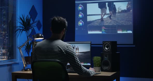 Young Man Sitting Back and Editing Video Inside a Room