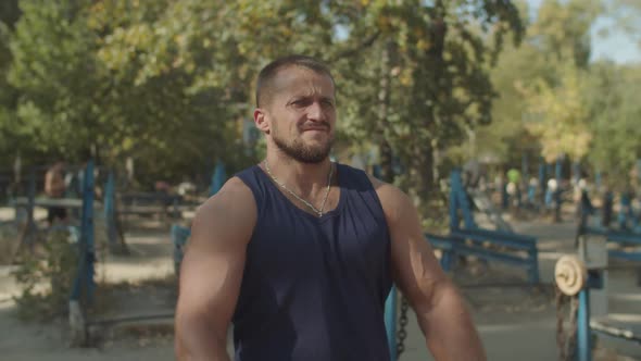 Strong Athlete Flexing His Muscles in Outdoor Gym