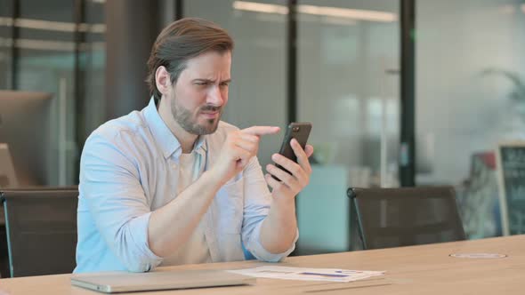 Mature Adult Man Reacting to Loss on Smartphone in Office