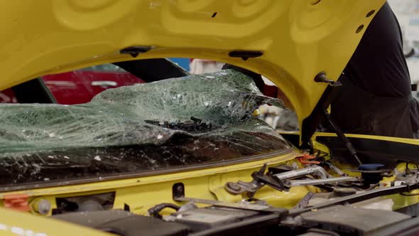 Mechanic Dismantles Broken Glass on Bright Yellow Car in Service