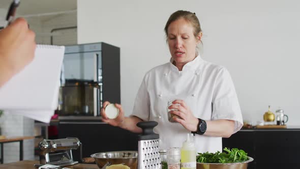 Caucasian female chef pouring spices into a dish