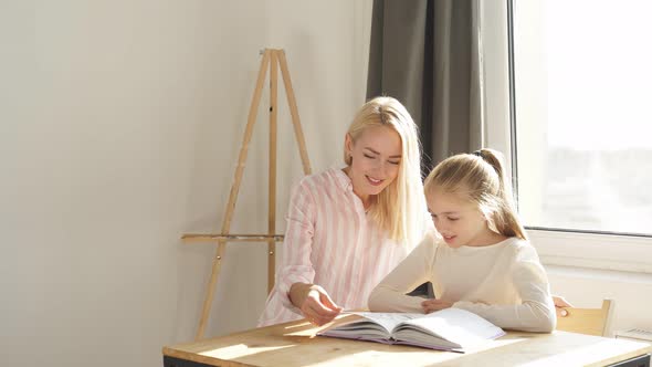 Young Parent Mum Helping Cute Caucasian School Child Girl Doing Homework