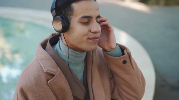 Cheerful Arabian man listening music in headphones