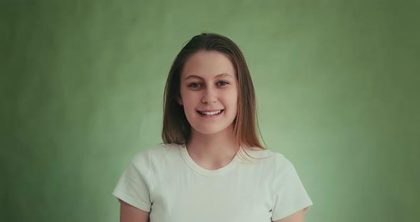 Positive Woman Smiles and Laughs Posing for Camera on Green