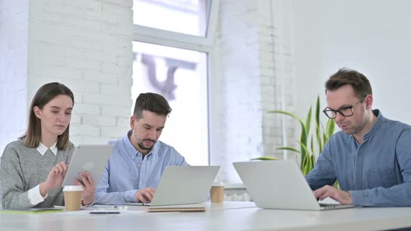 Serious Creative Startup Team Working on Laptop in Modern Office