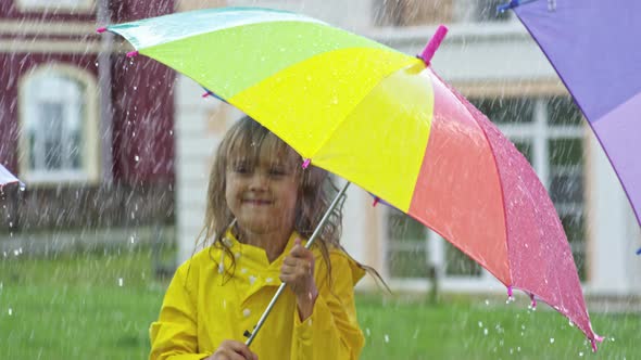 Cute Girl in Yellow Raincoat Jumping in Rain