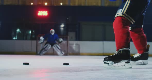 Close-up of a Hockey Puck in Slow Motion and a Putter of Several Pucks in Turn and a Goalkeeper