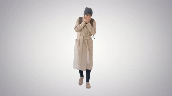 Woman in a Coat Walking and Coughing on Gradient Background