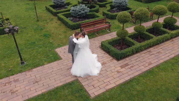 Newlyweds Bride Embracing Groom in Park Making Kiss Wedding Couple Family Hugging Aerial View