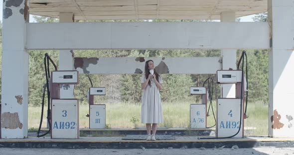 Young Woman Taking Off Pandemic Protective Mask on Abandoned Gas Station Background. Happy Girl