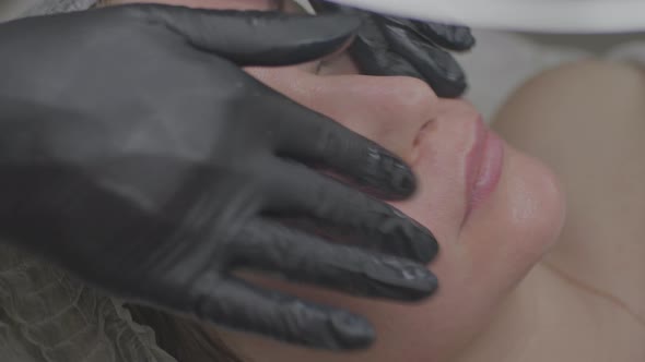 A Woman in a Beauty Salon Applies a Moisturizing Tissue Mask to Her Face