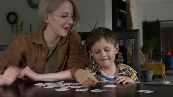 Mom teaches her son how to say the words on the cards at home at the table