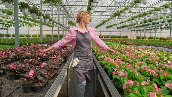 Happy Blonde Florist Gardener Enjoys Working in Her Greenhouse Walking Through Flower Saplings