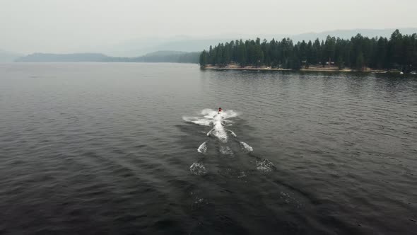 Drone shot following a woman on a jet ski driving on Payette Lake in McCall, Idaho on a smoky summer