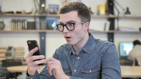 Creative Man in Glasses Reacting to Loss in Smartphone