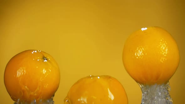 Group of Oranges is Bouncing From Water with Splashes on the Yellow Background