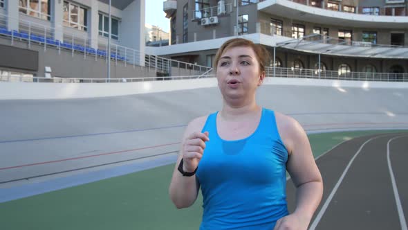 Active Plus Size Woman Running Along Stadium Track