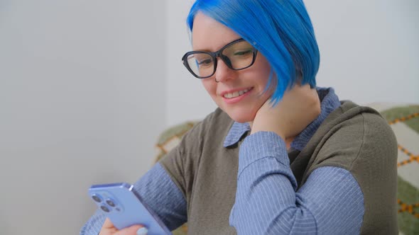 Cute white girl with blue hair browsing internet and social media on modern smartphone in 4k