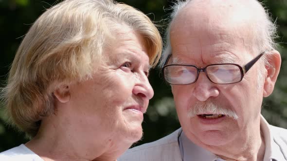 Calm senior couple sitting on a park bench talking