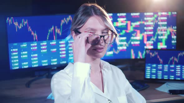 Female Stockbroker and Monitors with Stock Data Behind Her