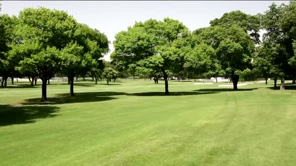 Drone footage of golf course fairway through trees