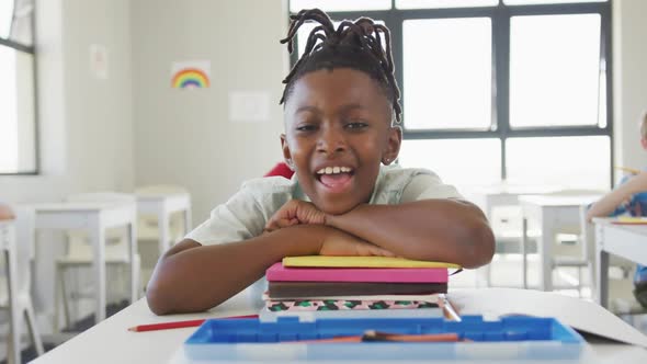 Video of happy african american boy sitting at school desk