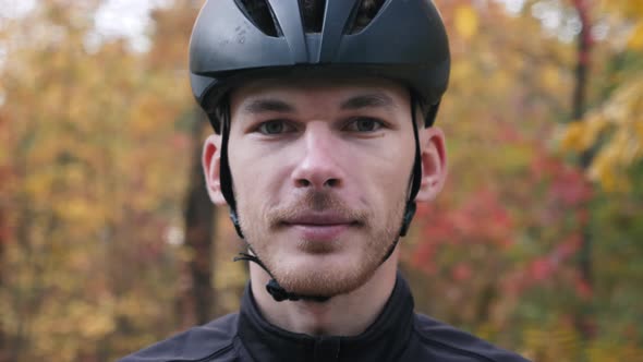 Portrait of cyclist or triathlete puts on sports sunglasses before cycling training. Close up shot